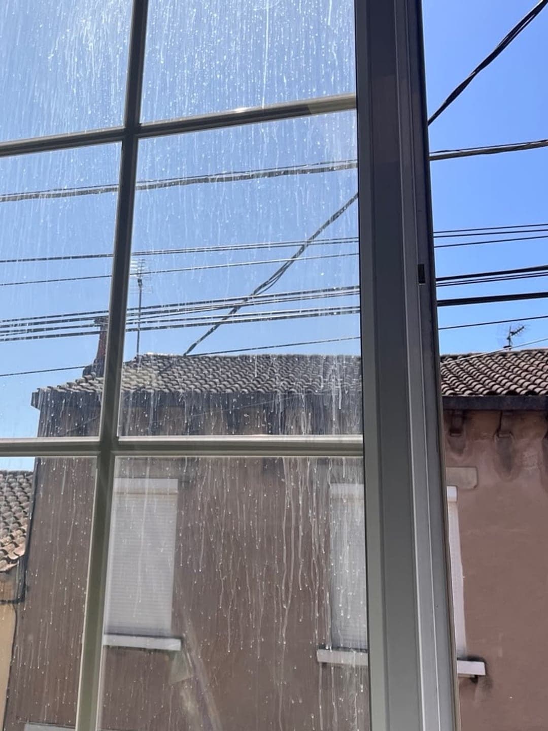 Fenêtre à petits bois marquée par les coulures de pluie