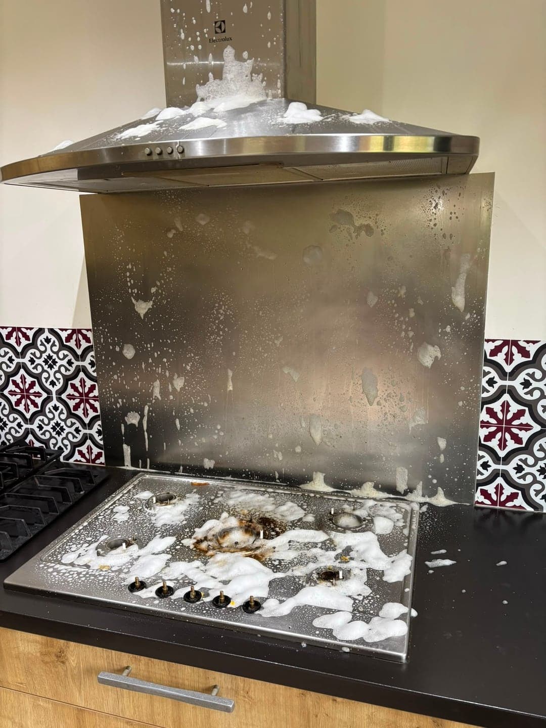 Hotte inox et plaque de cuisson couvertes de projections de graisse