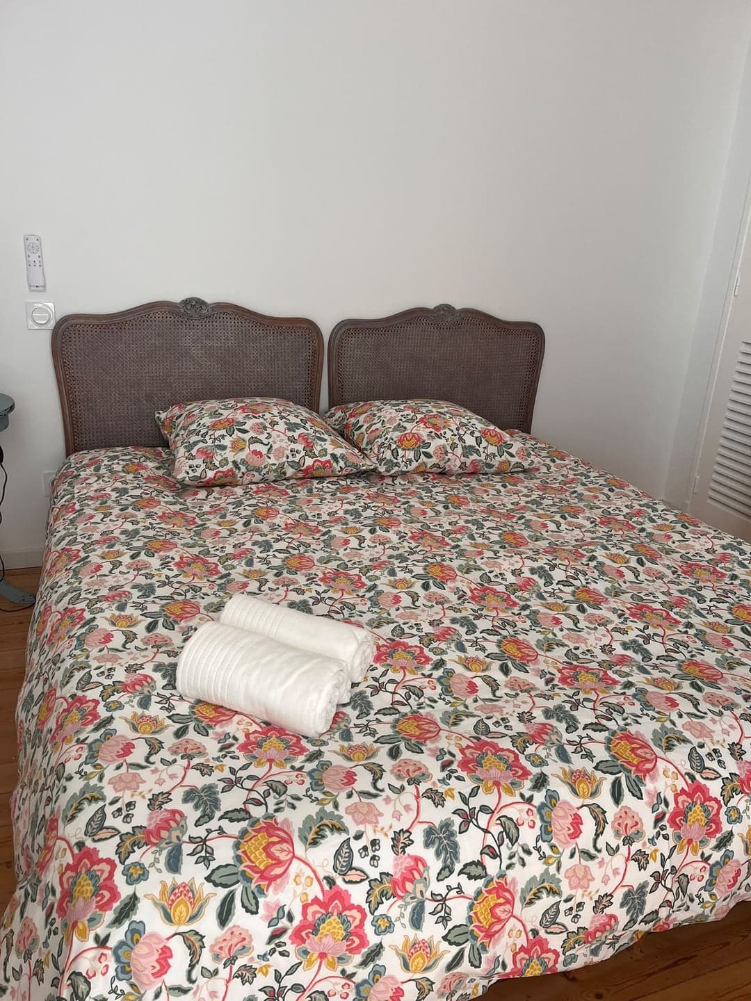 Chambre à literie fleurie et serviettes roulées, prête à l'arrivée