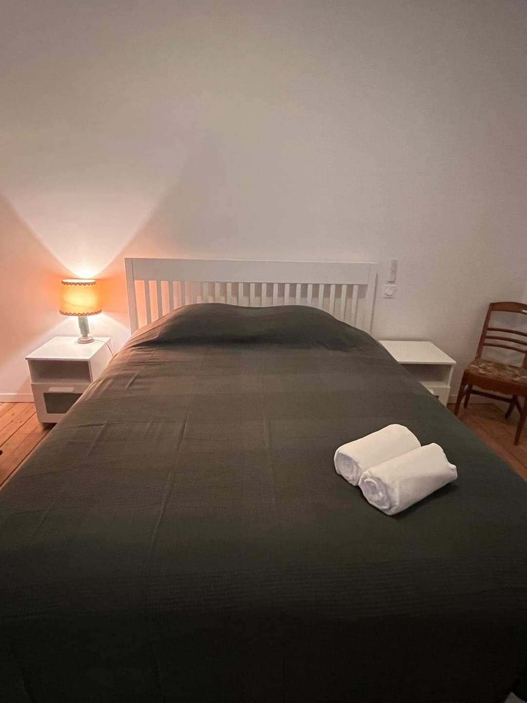 Chambre claire à couvre-lit vert et chevet allumé